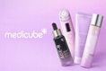 Stacked authentic Medicube skincare products including Age-R devices and Zero Pore pads on a lavender pink background with the official Medicube logo—authorized Seoul-direct collection for Pakistan markets at Korean Skincare Pakistan.